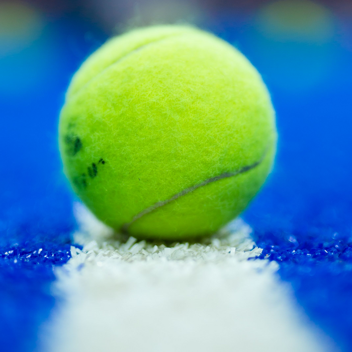 Padelball im Fokus, der auf der Linie eines Padelcourts liegt.