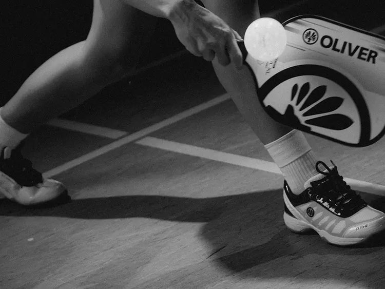 Pickleball Aktion mit OLIVER Schläger und Sportschuhen – Dynamische Schwarz-Weiß-Aufnahme auf dem Spielfeld