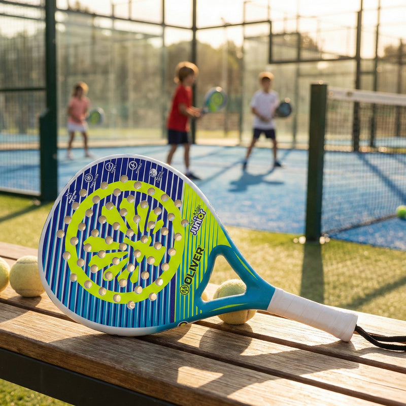 Padel Schläger OLIVER Air Max Junior in der Farbe blau-weiß mit gelbem Design liegt auf einer Holzbank mit Padelbällen. Im Hintergrund ist ein Padel Court mit Kindern abgebildet, die mit dem Padel Schläger Padel spielen.