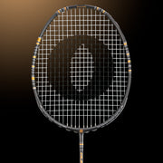 Oliver Badmintonschläger Modell Dual Tec, schwarzer Schläger mit goldenem Design vor einem dunklen goldenen Hintergrund