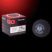 OLIVER Squashball in Schwarz mit der Verpackung links daneben auf dunklem Hintergrund
