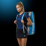Model mit OLIVER Sportkleidung und OLIVER Gearbag Extend in blau, grau und schwarzer Farbe auf dunklem Hintergrund.