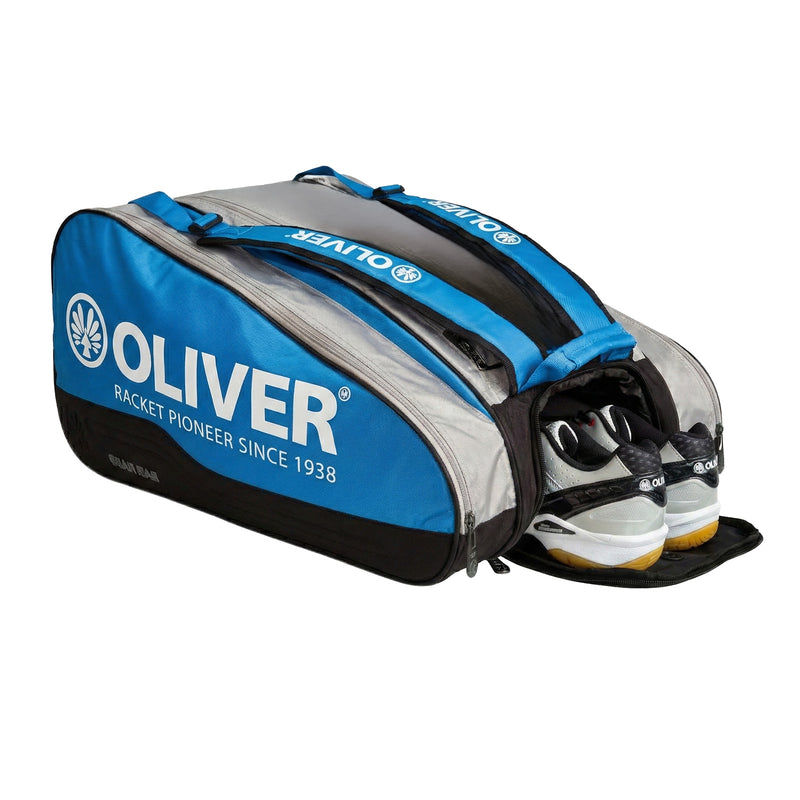 OLIVER Gearbag Extend in blau, grau und schwarzer Farbe mit geöffnetem Schuhfach und OLIVER CX Pro 12 Sportschuhen auf weißem Hintergrund.