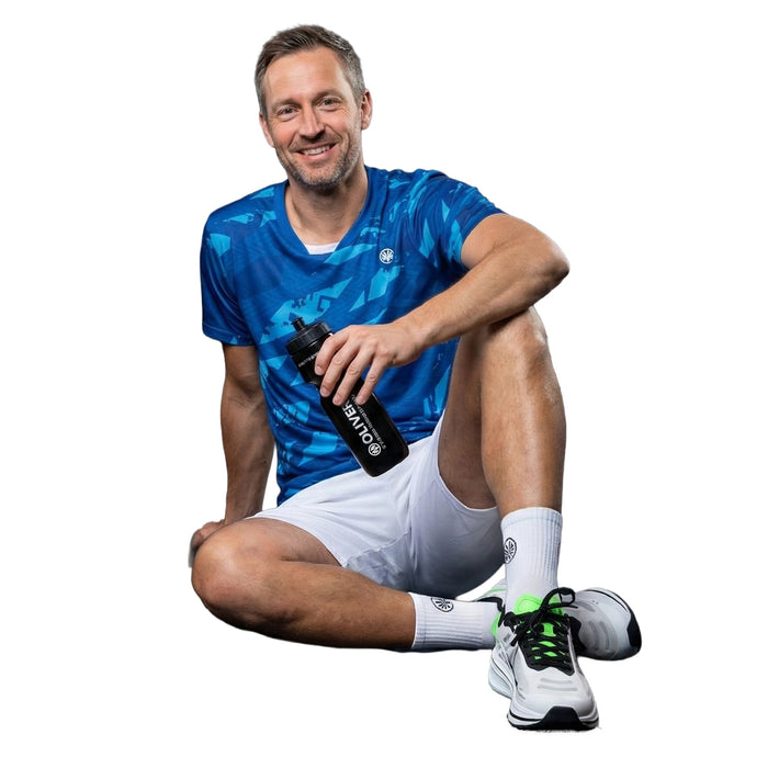 Sportler in OLIVER Sportbekleidung hält schwarze OLIVER Sport Trinkflasche mit weißem Logo und weißer Schrift auf weißem Hintergrund.